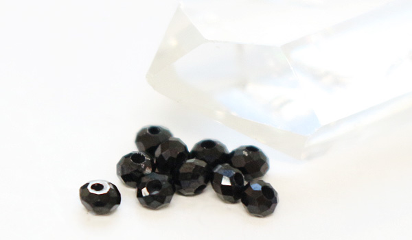 ブラックスピネルボタンカット3×2mmパーツパワーストーンビーズを水晶ポイントの前に置いて撮影